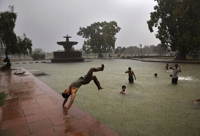 A boy somersaults into a water body as it rains in New Delhi, India, Wednesday, July 2, 2014. According to the weather office, the monsoon rains are expected to arrive at the national capital in a couple of days. (Photo by Manish Swarup/AP Photo)