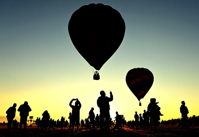 Spectators watch on as Hot Air Balloons take flight from Brown Brothers Milawa Airfield on March 27, 2022 in Wangaratta, Australia. The King Valley Balloon Fiesta runs from 25 to 27 March. This year the event's feature Special Shape is a 33m tall 3 toed sloth called Tico. (Photo by Quinn Rooney/Getty Images)