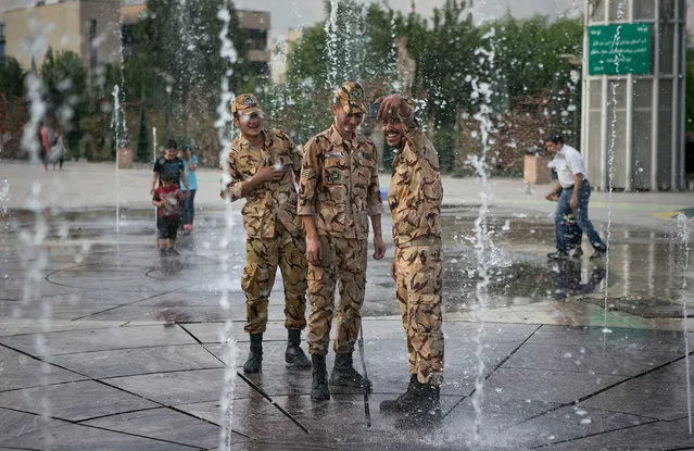 Iranian soldiers take pictures as they cool off themselves in the water of a fountain during hot weather at a park in Tehran, Iran, on July 17, 2017. (Photo by Xinhua/Barcroft Images)