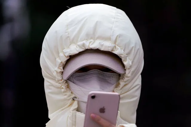 A woman wearing a mask checks her mobile phone in Shanghai, China on January 29, 2020. (Photo by Aly Song/Reuters)