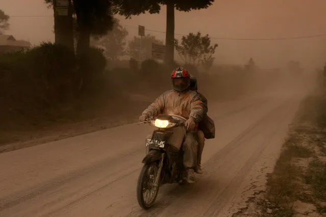 A motorist rides his motorbike following an eruption of Mount Sinabung volcano, in Beganding Village, Karo, North Sumatra, Indonesia August 2, 2017. (Photo by Y.T. Haryono/Reuters)