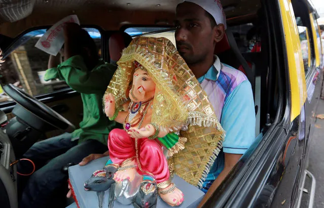 A devotee transports an idol of the Hindu god Ganesh, the deity of prosperity, in a taxi to a place of worship on the first day of the ten-day-long Ganesh Chaturthi festival in Mumbai, India August 25, 2017. (Photo by Danish Siddiqui/Reuters)
