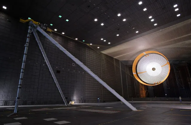 The parachute for NASA's Mars Science Laboratory passed flight-qualification testing in March and April 2009 inside the world's largest wind tunnel, at NASA Ames Research Center, Moffett Field, California. In this image, an engineer is dwarfed by the parachute, the largest ever built to fly on an extraterrestrial flight. It is designed to survive deployment at Mach 2.2 in the Martian atmosphere, where it will generate up to 65,000 pounds of drag force. The parachute has 80 suspension lines, measures more than 50 meters (165 feet) in length, and opens to a diameter of nearly 16 meters (51 feet). (Photo by NASA/Ames Research Center/JPL)