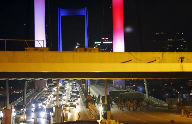 Turkish soldiers block Istanbul's iconic Bosporus Bridge on Friday, July 15, 2016, lit in the colours of the French flag in solidarity with the victims of Thursday's attack in Nice, France. A group within Turkey's military has engaged in what appeared to be an attempted coup, the prime minister said, with military jets flying over the capital and reports of vehicles blocking two major bridges in Istanbul. (Photo by Emrah Gurel/AP Photo)