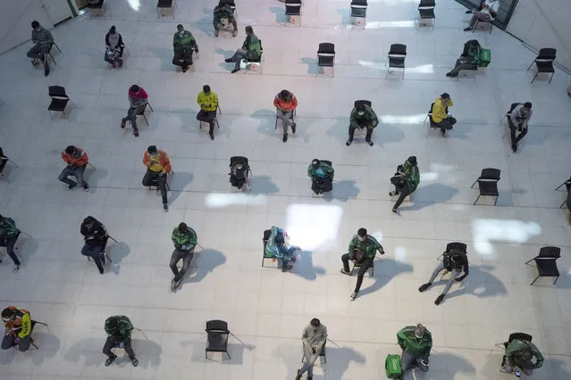 People practice social distancing as they sit on chairs spread apart in a waiting area for take-away food orders at a shopping mall in hopes of preventing the spread of the coronavirus in Bangkok, Thailand, Tuesday, March 24, 2020. (Photo by Sakchai Lalit/AP Photo)