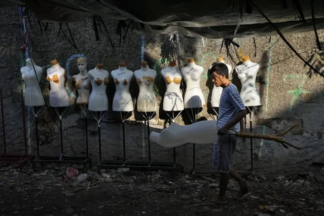 A worker collects mannequins torsos at the Tanah Abang textile market in Jakarta, Indonesia, Monday, June 20, 2022. (Photo by Tatan Syuflana/AP Photo)