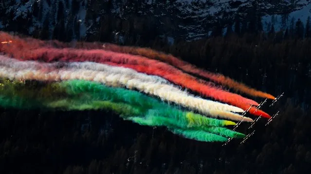 Planes of the Italian Air Force aerobatic unit Frecce Tricolori (Tricolor Arrows) spread smoke with the colors of the Italian flag as they perform over Alta Badia, Dolomite Alps, on December 19, 2021 within the men's FIS Ski World Cup Giant Slalom event. (Photo by Tiziana Fabi/AFP Photo)