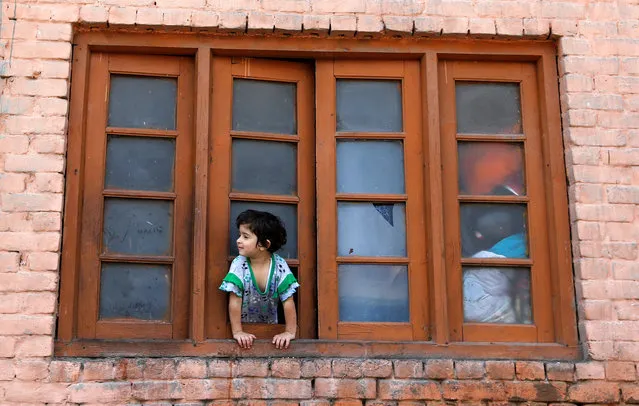 A girl looks out from a window of her house during a curfew in Srinagar, July 24, 2016. (Photo by Danish Ismail/Reuters)