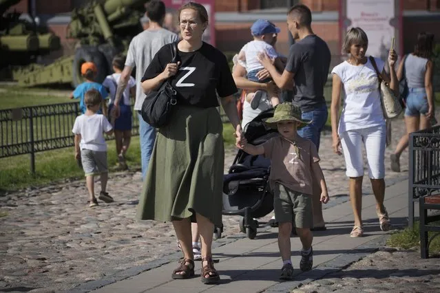 A woman and her child wearing t-shirts with letter Z, which has become a symbol of the Russian military walk in the Artillery museum in St. Petersburg, Russia, Saturday, August 20, 2022. (Photo by Dmitri Lovetsky/AP Photo)