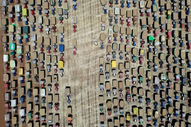 In this aerial photo taken on April 21, 2020, farmers line up their tractors carrying wheat grain at a wholesale market during a government-imposed nationwide lockdown as a preventive measure against the COVID-19 novel coronavirus, at Majholi Tehsil village, some 45 km from Jabalpur. (Photo by Uma Shankar Mishra/AFP Photo)