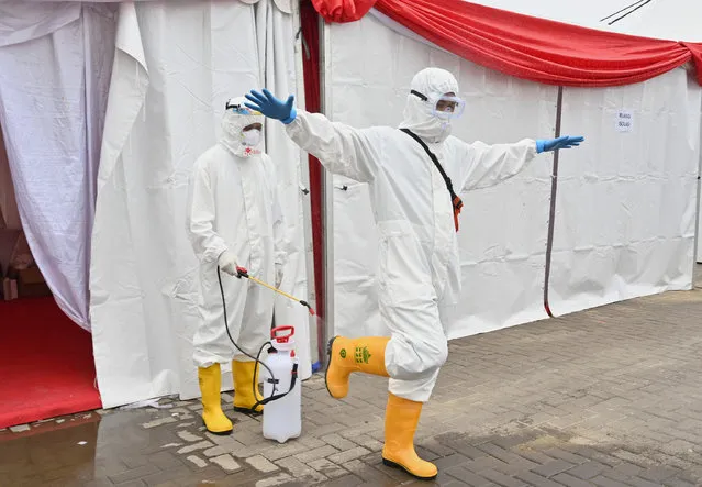 A volunteer sprays disinfectant on a doctor after conducting rapid tests for the COVID-19 coronavirus in the Kemayoran area in Jakarta on April 28, 2020. (Photo by Adek Berry/AFP Photo)