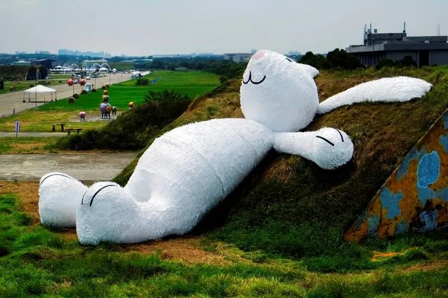Dutch artist Florentijn Hofman's latest creation, a 25 meter (82 feet) white rabbit, leans up against an old aircraft hangar as part of the Taoyuan Land Art Festival in Taoyuan, Taiwan, Tuesday, September 2, 2014. Hofman's big yellow duck drew millions of visitors as it toured the island last year and festival organizers are hoping the rabbit will do the same. The Taoyuan Land Art Festival will take place from September 9-14. (Photo by Wally Santana/AP Photo)