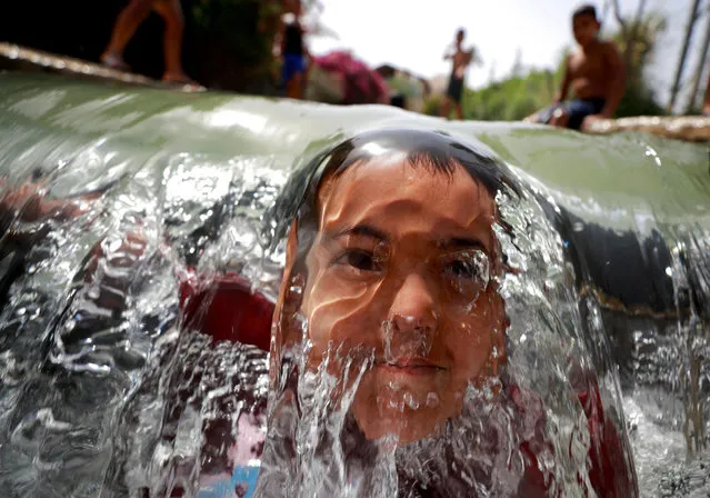 A Palestinian boy dips in a natural spring to cool off during a heat wave, amid concerns about the spread of the coronavirus disease (COVID-19), near Jericho in the Israeli-occupied West Bank on May 17, 2020. (Photo by Mohamad Torokman/Reuters)
