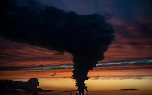 A red and blue colored sky is pictured at sunset as steam rises from the chimneys of Niederaussen lignite-fired power plant in Roggendorf, western Germany on November 8, 2019. (Photo by Federico Gambarini/dpa/AFP Photo)