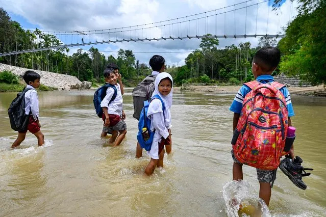 Young pupils cross a river from a primary school at Siron village in Kuta Cot Glie, Aceh province, Indonesia on October 4, 2022. (Photo by Chaideer Mahyuddin/AFP Photo)