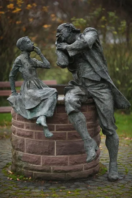 A bronze sculpture depicts a grandfather recounting a fairy tale to his dranddaughter on November 19, 2012 in Schoeneberg, Germany. Schoeneberg lies along the “Fairy Tale Road” (in German: Die Maerchenstrasse) that leads through the region between Frankfurt and Bremen where the Grimm brothers collected and adapted most of their fairy tales, which include such global classics as Sleeping Beauty, Little Red Riding Hood, Rapunzel, Cinderella and Hansel and Gretel, in the early 19th century. The 200th anniversary of the first publication of the stories will take place this coming December 20th.  (Photo by Sean Gallup)