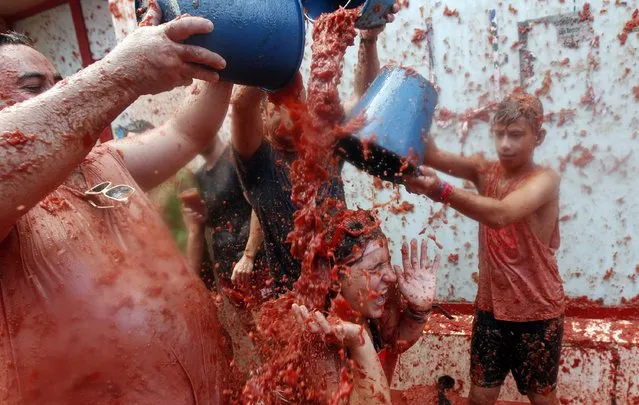 A woman is covered in tomato as she takes part during the traditional annual tomato fight, known as “Tomatina” in Bunol, eastern Spain, 31 August 2016. As every year on the last Wednesday of August, thousands visit the small village of Bunol to attend the world-wide known Tomatina, a battle in wich assistants will use 160 of tons of tomatoes against each other. This year, the Tomatina demands the end of violence against women and homophobia. (Photo by Kai Forsterling/EPA)