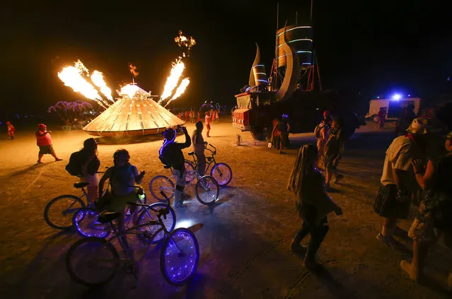 In this Tuesday, August 30, 2016 photo, attendees walk by art cars during Burning Man at the Black Rock Desert near Gerlach, Nev. (Photo by Chase Stevens/Las Vegas Review-Journal via AP Photo)