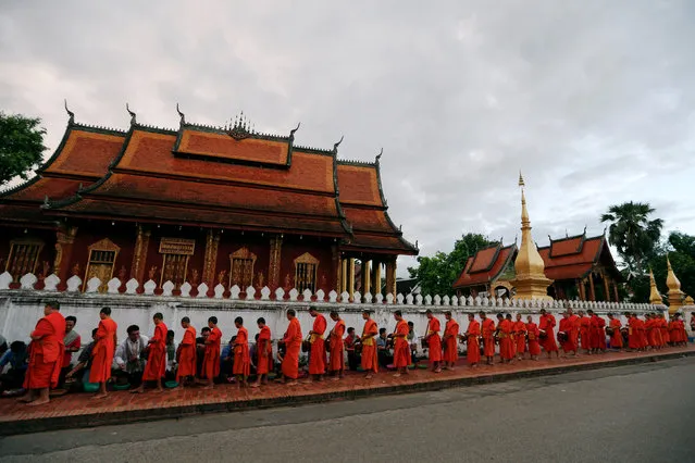 Buddhist monks walk while collecting alms early morning in front of Wat Sene Buddhist temple in Luang Prabang, Laos July 31, 2016. (Photo by Jorge Silva/Reuters)