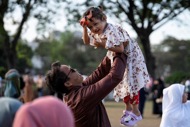 A man lifts a child as they take family pictures after Eid al-Fitr prayers at Quirino Grandstand, in Manila, Philippines, on March 31, 2025. (Photo by Lisa Marie David/Reuters)