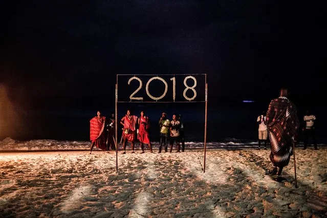 People wait for a moment to light a sign that reads 2018 during the New Year's Eve celebration on Nungwi Beach in Zanzibar, Tanzania, on December 31, 2017. (Photo by Gulshan Khan/AFP Photo)