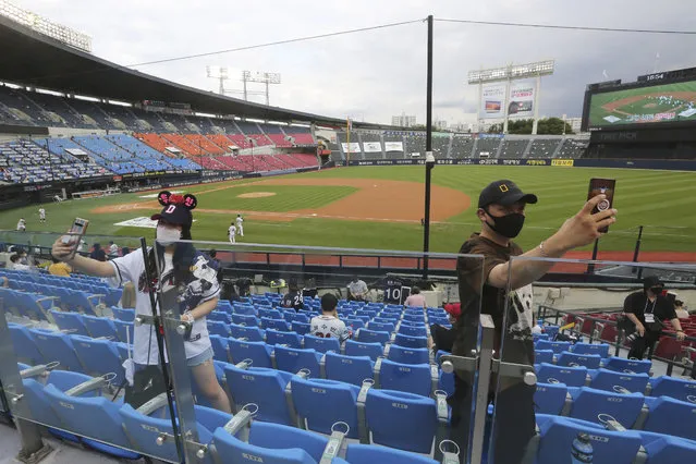 In this July 27, 2020, file photo, fans wearing face masks to help protect against the spread of the new coronavirus take a selfie before the KBO league game between Doosan Bears and LG Twins in Seoul. South Korea may have been way ahead of the international curve in getting sport back to some semblance of normality but instead of near-full stadiums watching the end of baseball and soccer seasons later this year, a recent spike in coronavirus cases means officials will settle for just finishing the season at all. (Photo by Ahn Young-joon/AP Photo/File)
