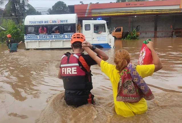 A handout photo made available by the Bureau of Fire Protection (BFP) shows a fire rescue personnel holding a resident on a flooded street on Christmas day in Gingoog city, Misamis Oriental province, Philippines, 25 December 2022. Intense rain brought by a weather occurrence called “Shear line” caused flooding in southern Philippines that resulted in the death of at least seven villagers. (Photo by Bfp Handout/EPA/EFE/Rex Features/Shutterstock)