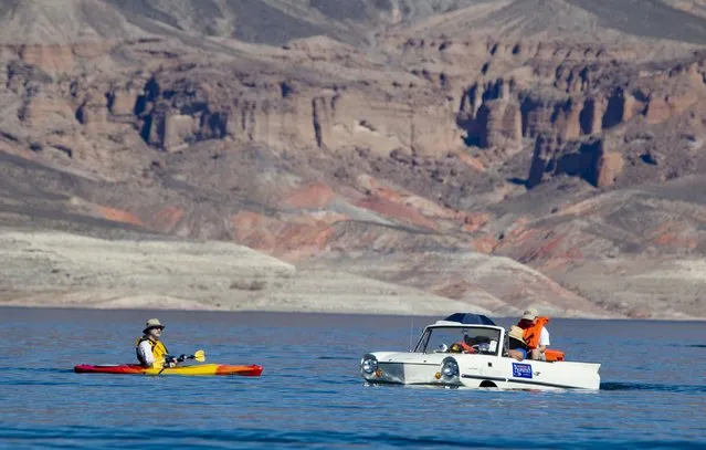 A kayaker looks over a 1965 Amphicar, driven by Dean Baker of Lake Havasu, Arizona, during the first Las Vegas Amphicar Swim-in at Lake Mead near Las Vegas, Nevada October 9, 2015. (Photo by Steve Marcus/Reuters)