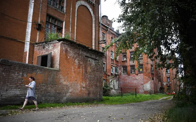 A woman walks past one of the buildings of a dormitory for the workers of Proletarka textile factory in the town of Tver, 200 kilometres north-west from Moscow on August 8, 2020. The golden age of Proletarka, the unique set of barracks, some fifty neo-Gothic buildings, including two decorated with gold medals at the Universal Exhibition of 1900 in Paris, ended with the break-up of the USSR in 1991 and the arrival of the market economy which opened the borders to inexpensive Chinese textiles. The famous Tver factory, created by cotton magnates Morozov, in 19th century, no longer existed, and its unique city, still overpopulated, was forgotten by the new authorities and turned into a dirty poor ghetto. (Photo by Andrey Borodulin/AFP Photo)