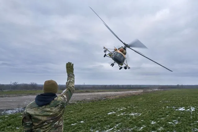 A Ukrainian soldier waves to a military helicopter returning from the combat, close to the frontline in the Kherson region, Ukraine, Sunday, January 8, 2023. (Photo by LIBKOS/AP Photo)