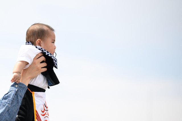 A parent holds his child before the start of the “crying baby sumo” match at the Sensoji temple in Tokyo on April 26, 2025. (Photo by Philip Fong/AFP Photo)