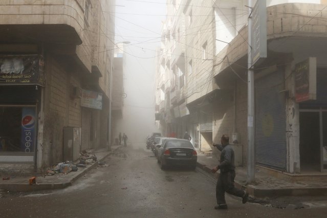 A man runs while pointing at a site hit by what activists said were airstrikes by forces loyal to Syria's President Bashar al-Assad in Raqqa, eastern Syria, which is controlled by the Islamic State November 27, 2014. (Photo by Nour Fourat/Reuters)