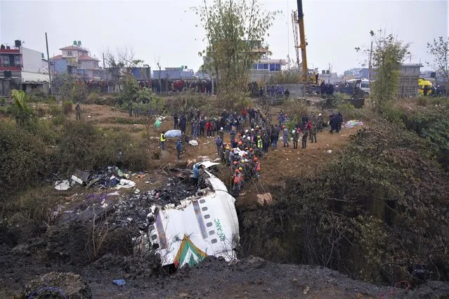 Rescuers scour the crash site in the wreckage of a passenger plane in Pokhara, Nepal, Monday, January16, 2023. Nepal began a national day of mourning Monday as rescue workers resumed the search for six missing people a day after a plane to a tourist town crashed into a gorge while attempting to land at a newly opened airport, killing at least 66 of the 72 people aboard in the country's deadliest airplane accident in three decades. (Photo by Yunish Gurung/AP Photo)