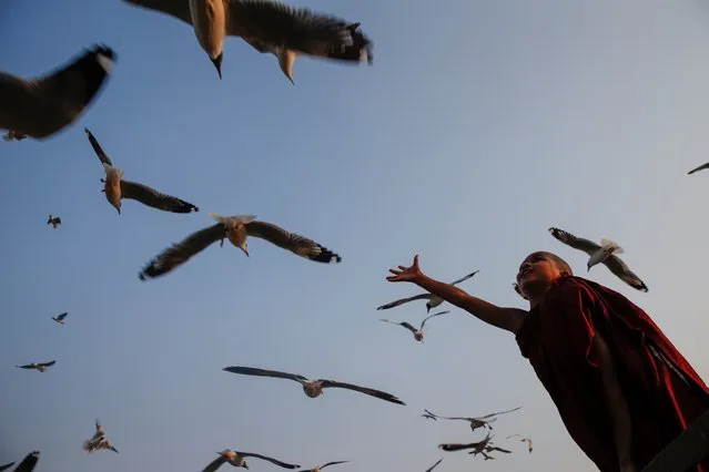 A young Buddhist novice enjoys the evening as gulls fly around a jetty in Rangoon, Burma on March 20, 2018. (Photo by Lynn Bo Bo/EPA/EFE/Rex Features/Shutterstock)