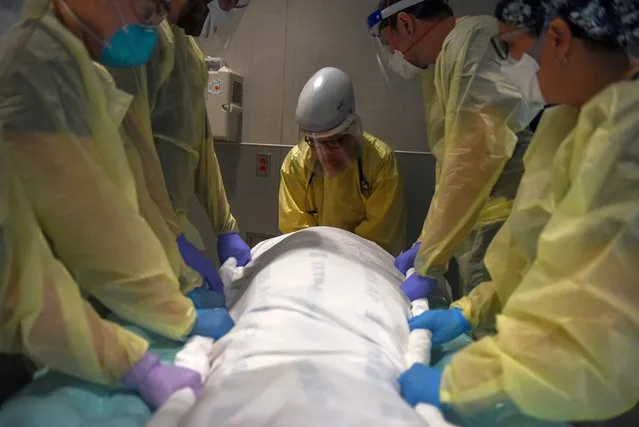 Healthcare personnel prepare to rotate a patient who is on a ventilator inside a room for patients with the coronavirus disease (COVID-19) at a hospital in Hutchinson, Kansas, U.S., November 20, 2020. (Photo by Callaghan O'Hare/Reuters)