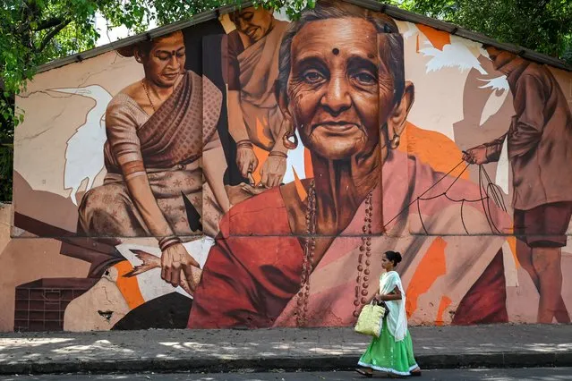 A woman walks past a mural of depicting fisherwomen, in Mumbai on April 5, 2023. (Photo by Punit Paranjpe/AFP Photo)