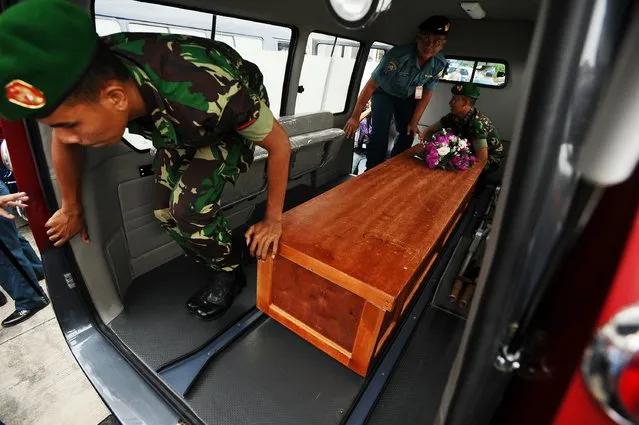 Indonesian soldiers place a coffin containing a victim of the AirAsia flight QZ8501 crash into a vehicle at Indonesian Military Base Airport on December 31, 2014 in Surabaya, Indonesia. (Photo by Robertus Pudyanto/Getty Images)