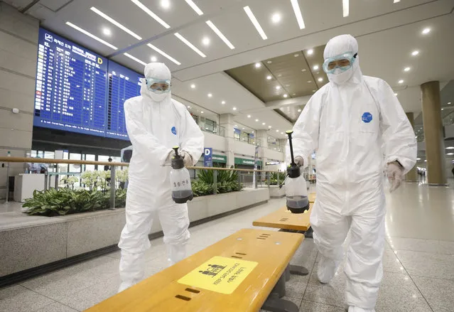 Workers wearing protective gears disinfect chairs as a precaution against the coronavirus at the arrival hall of the Incheon International Airport in Incheon, South Korea, Tuesday, December 29, 2020. South Korea says 40 more coronavirus patients have died in the past 24 hours, the highest daily fatalities since the pandemic began, as the country is grappling with surging cases in recent weeks. (Photo by Ko Seung-min/Newsis via AP Photo)