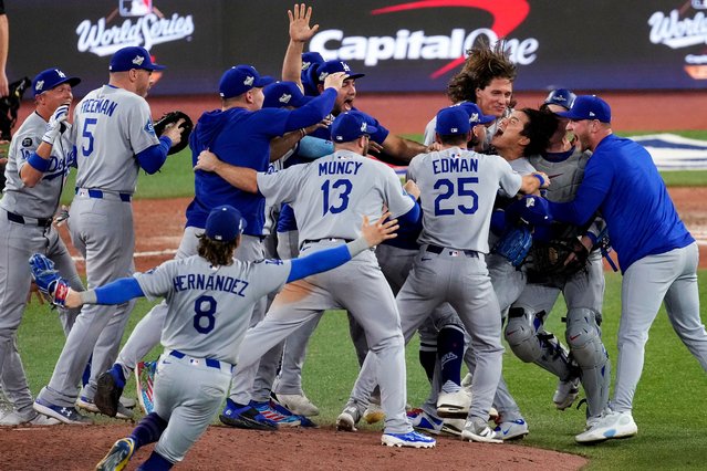 The Los Angeles Dodgers surround pitcher Yoshinobu Yamamoto as they celebrate their World Series title win against the Toronto Blue Jays, at the end of Game 7 in Toronto, November 2, 2025. (Photo by Ashley Landis/AP Photo)