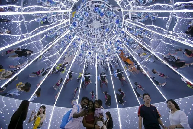 People are reflected on mirrors as they take photos inside a giant Christmas tree in the shopping district of Orchard Road in Singapore December 9, 2015. (Photo by Edgar Su/Reuters)