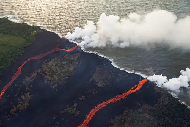 Two rivers of lava enter the sea on May 24, 2018 in Hawaii, USA, as multiple fissure eruptions supplied a tremendous volume of molten material, and the interaction between the cold seawater and 2000 degree lava create a toxic gas plume of laze. Consisting of hydrochloric acid, steam, and tiny bits of volcanic glass, this mixture irritates and burns, and can cause respiratory issues. (Photo by Bruce Omori/Paradise Helicopters/ZUMA Wire/Rex Features/Shutterstock)