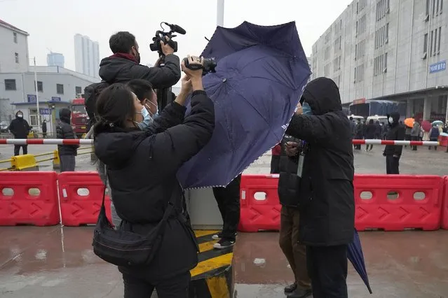 A plainclothes security person uses his umbrella to block journalists from filming after the World Health Organization team arrive at the Baishazhou wholesale market on the third day of field visit in Wuhan in central China's Hubei province on Sunday, January 31, 2021. WHO says the team plans to visit hospitals, markets and laboratories in a politically charged mission as China seeks to avoid blame for alleged early missteps. A single visit by scientists is unlikely to confirm the virus’s origins. (Photo by Ng Han Guan/AP Photo)