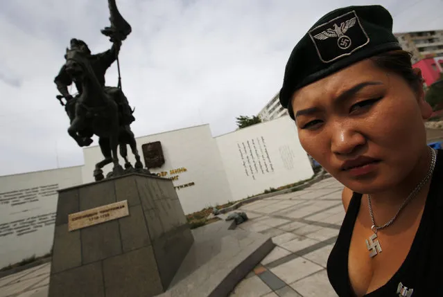 Uranjargal, a leader of the Mongolian neo-Nazi group Tsagaan Khass, stands next to a statue of Chingunjav, a Mongolian national hero, in Ulan Bator June 22, 2013. (Photo by Carlos Barria/Reuters)