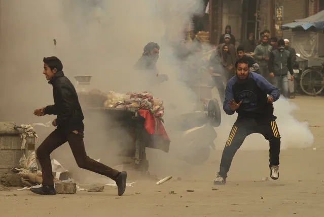 Kashmiri protesters run as a tear gas shell explodes near them during a protest against the government in Srinagar, India, Monday, December 14, 2015. (Photo by Mukhtar Khan/AP Photo)