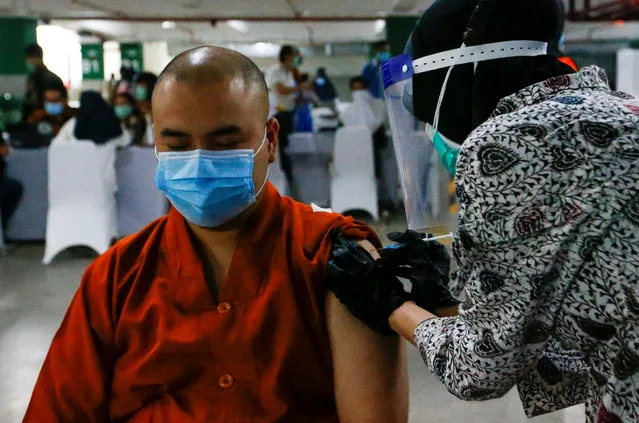 A monk reacts while receiving the first dose of China's Sinovac Biotech vaccine for the coronavirus disease (COVID-19) during the mass vaccination program for clergy at the parking lot of Grand Istiqlal Mosque in Jakarta, Indonesia, February 25, 2021. (Photo by Ajeng Dinar Ulfiana/Reuters)