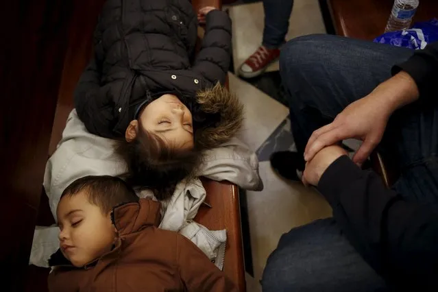 Children sleep on a pew before the start of a distribution of free toys for low-income families and a picture on the lap of one of the Three Wise Men at Almudena Cathedral in Madrid, Spain, December 22, 2015. (Photo by Susana Vera/Reuters)