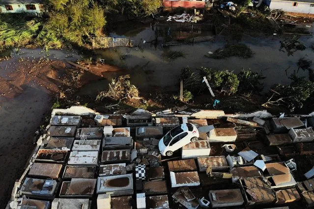 Aerial view of a destroyed car on top of tombstones at the cemetery after a cyclone in Caraa, Brazil on June 19, 2023. A cyclone which tore through southern Brazil has killed at least 13 people and forced thousands from their homes, authorities said Sunday. Torrential rain and strong winds on Thursday and Friday caused damage in dozens of towns in the state of Rio Grande do Sul, including its capital Porto Alegre – the latest in a string of weather-related disasters to hit South America's biggest country. Two more bodies were discovered in the coastal town of Caraa, one of the hardest hit, bringing the death toll from the storm to 13, the state civil defense agency said. (Photo by Silvio Avila/AFP Photo)