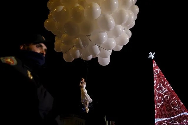 A Spanish police officer (L) stands guard as an acrobatic performer goes airborne during the traditional Epiphany parade in Madrid, Spain, January 5, 2016. (Photo by Susana Vera/Reuters)