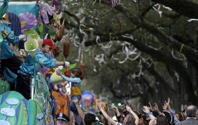 A float rider puts beads around the neck of a child during Krewe of Proteus Mardi Gras parade in New Orleans, Monday, February 16, 2015. The day is known as Lundi Gras, the day before Mardi Gras. (Photo by Gerald Herbert/AP Photo)