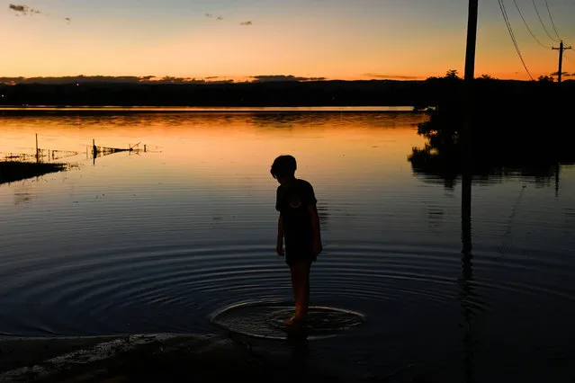 A boy stands on the edge of the floodwaters in the suburb of McGraths Hill as the state of New South Wales experiences widespread flooding and severe weather, near Sydney, Australia, March 24, 2021. (Photo by Jaimi Joy /Reuters)